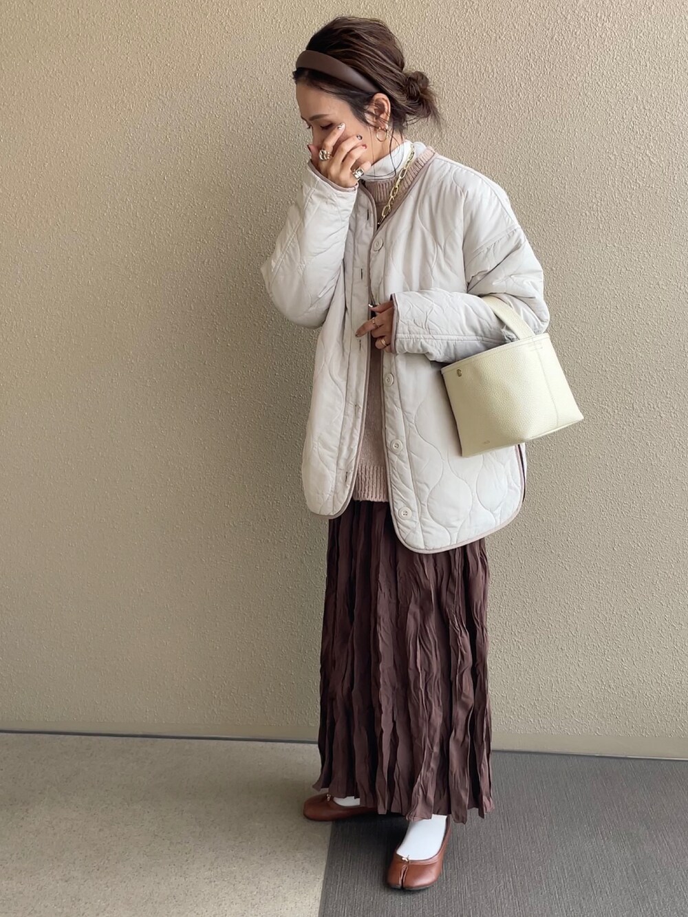 ベージュ系のニット/セーター、ブラウン系のスカート、ブラウン系のパンプスを着用したレディースの冬コーディネートの2枚目の写真