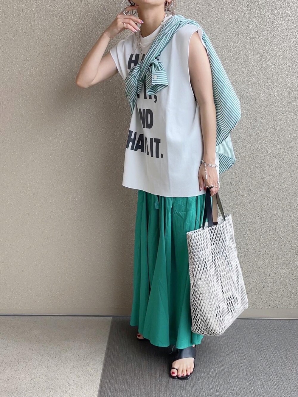 グリーン系のスカート、ホワイト系のトップス、ホワイト系のバッグを着用したレディースの春コーディネートの2枚目の写真