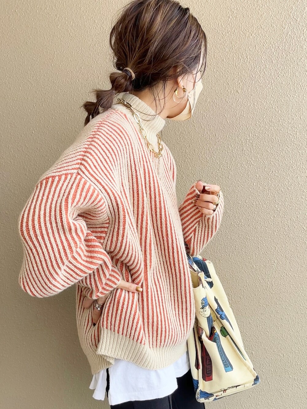 オレンジ系のニット/セーター、ブラック系のその他パンツ、ホワイト系のトートバッグを着用したレディースの冬コーディネートの3枚目の写真