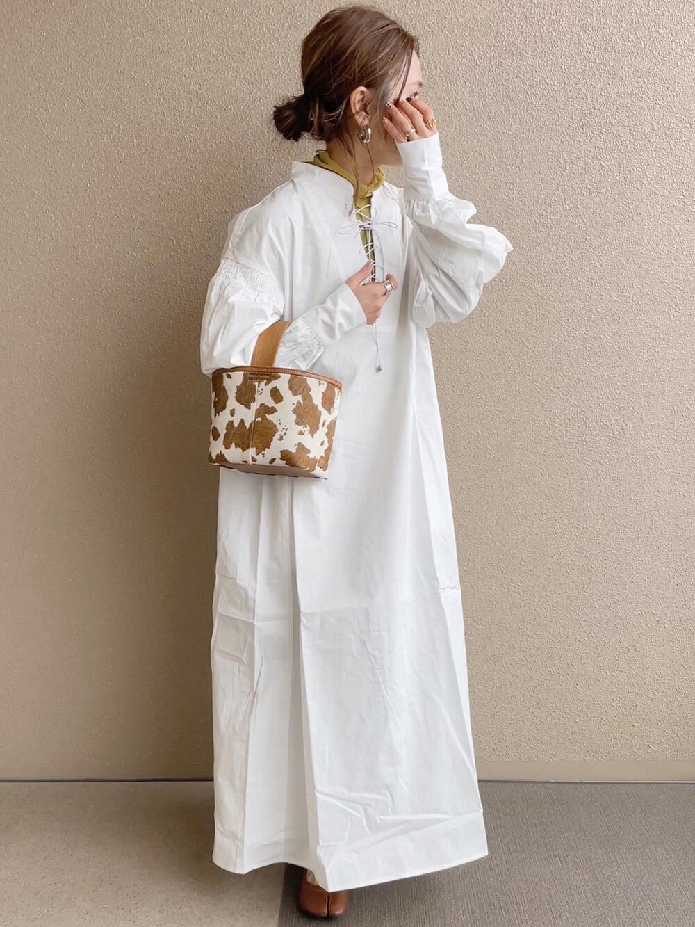 ホワイト系のワンピース、グリーン系のTシャツ/カットソー、ベージュ系のハンドバッグを着用したレディースの冬コーディネートの2枚目の写真