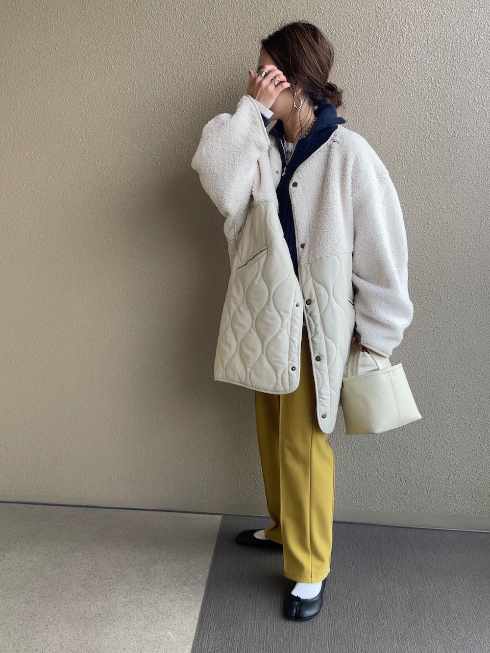 ホワイト系のノーカラージャケット、ブルー系のニット/セーター、イエロー系のその他パンツを着用したレディースの冬コーディネートの4枚目の写真