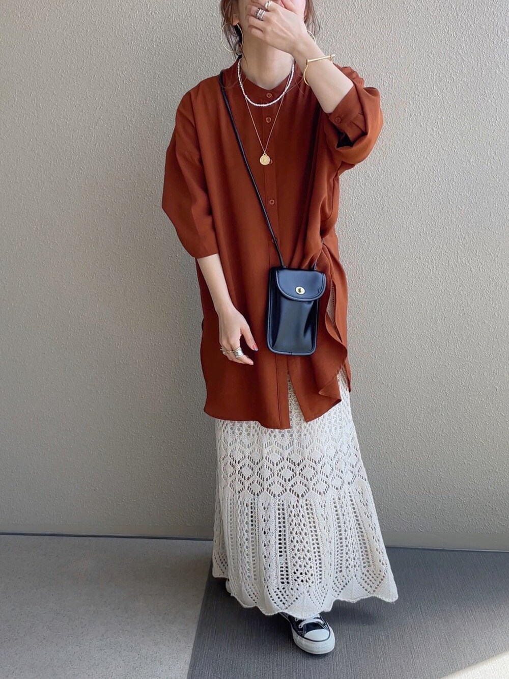 ホワイト系のスカート、ブラック系のTシャツ/カットソー、ブラウン系のベストを着用したレディースの春コーディネートの2枚目の写真