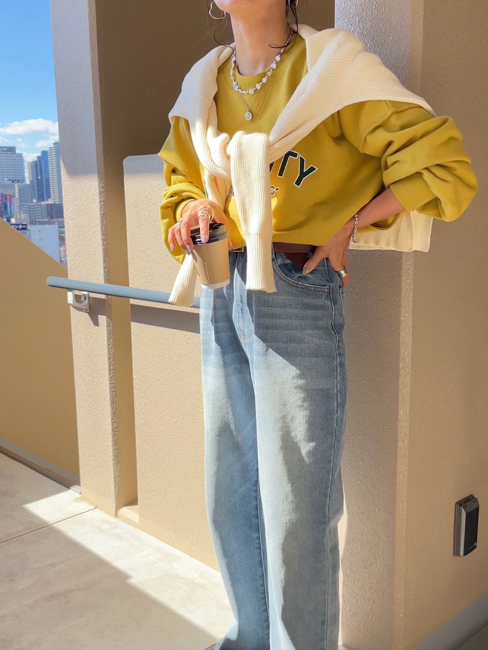 イエロー系のスウェット、ブルー系のデニムパンツを着用したレディースの秋コーディネートの3枚目の写真