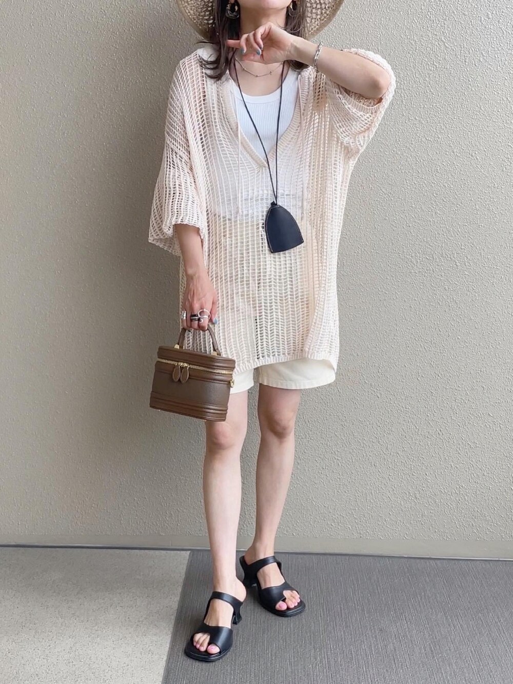 ホワイト系のパンツ、ホワイト系のニット/セーター、ブラウン系のサンダルを着用したレディースの夏コーディネートの3枚目の写真