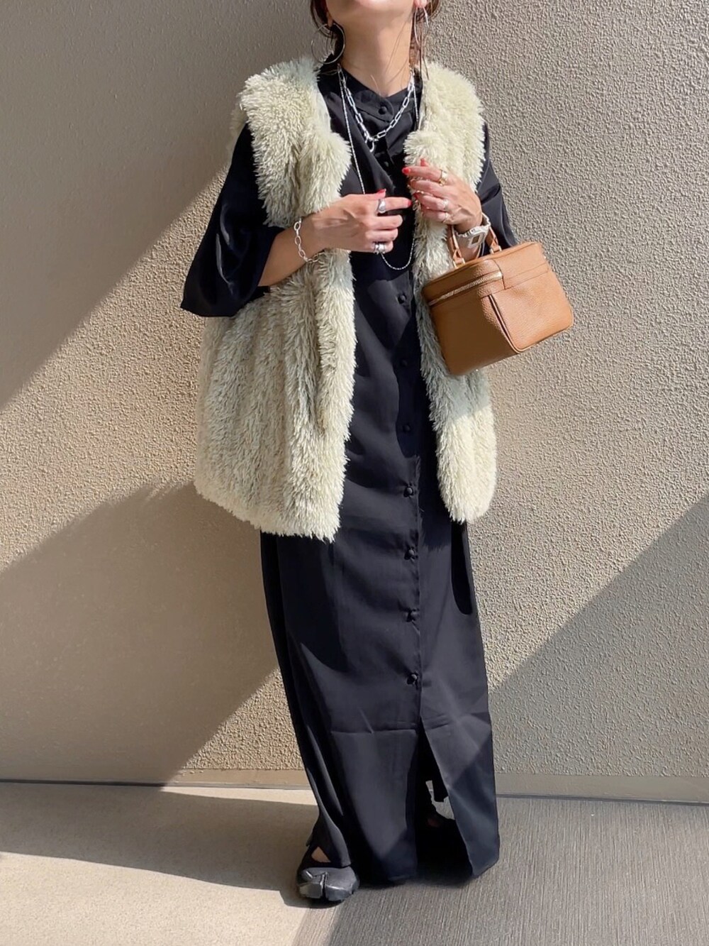 ブラック系のワンピース、ブラック系のサンダル、グリーン系のベストを着用したレディースの夏コーディネートの3枚目の写真