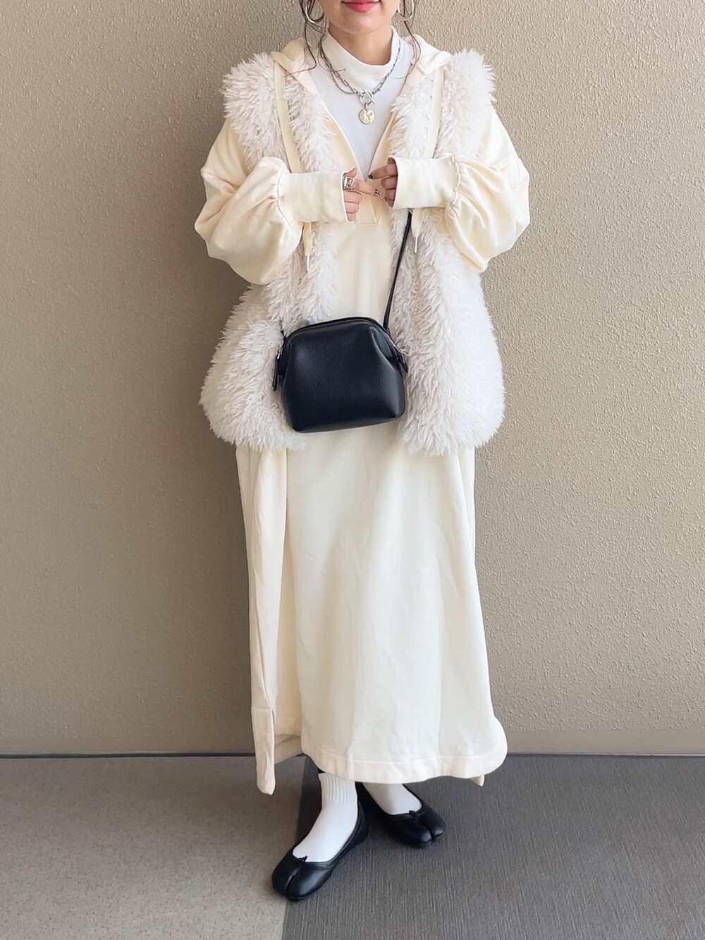 ホワイト系のワンピース、ホワイト系のベスト、グレー系のショルダーバッグを着用したレディースの冬コーディネートの3枚目の写真