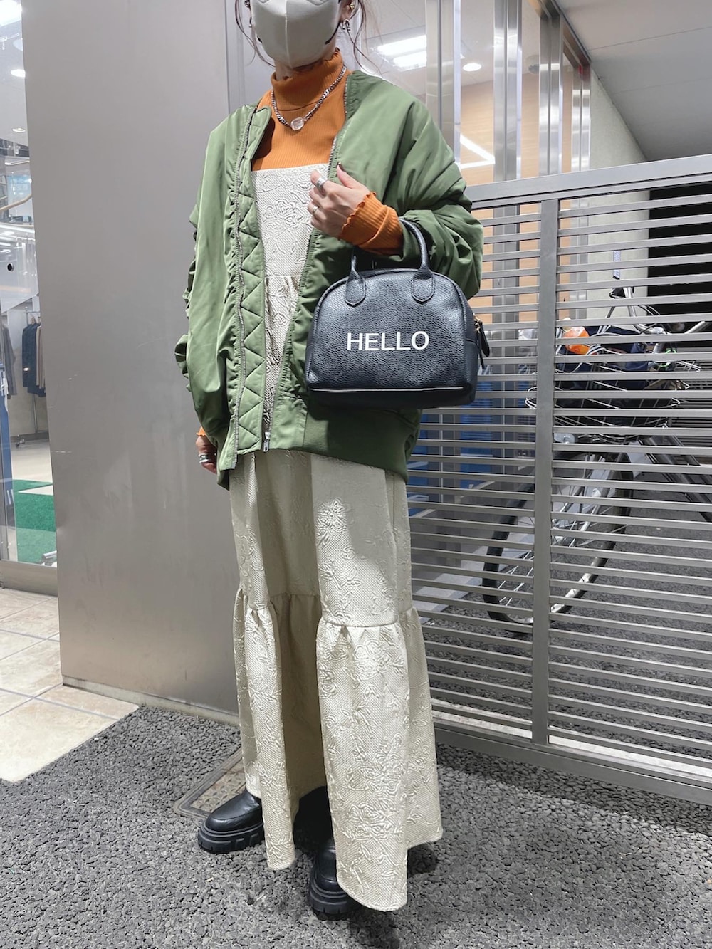 ブラック系のハンドバッグ、グリーン系のMA-1、オレンジ系のTシャツ/カットソーを着用したレディースの秋コーディネートの3枚目の写真