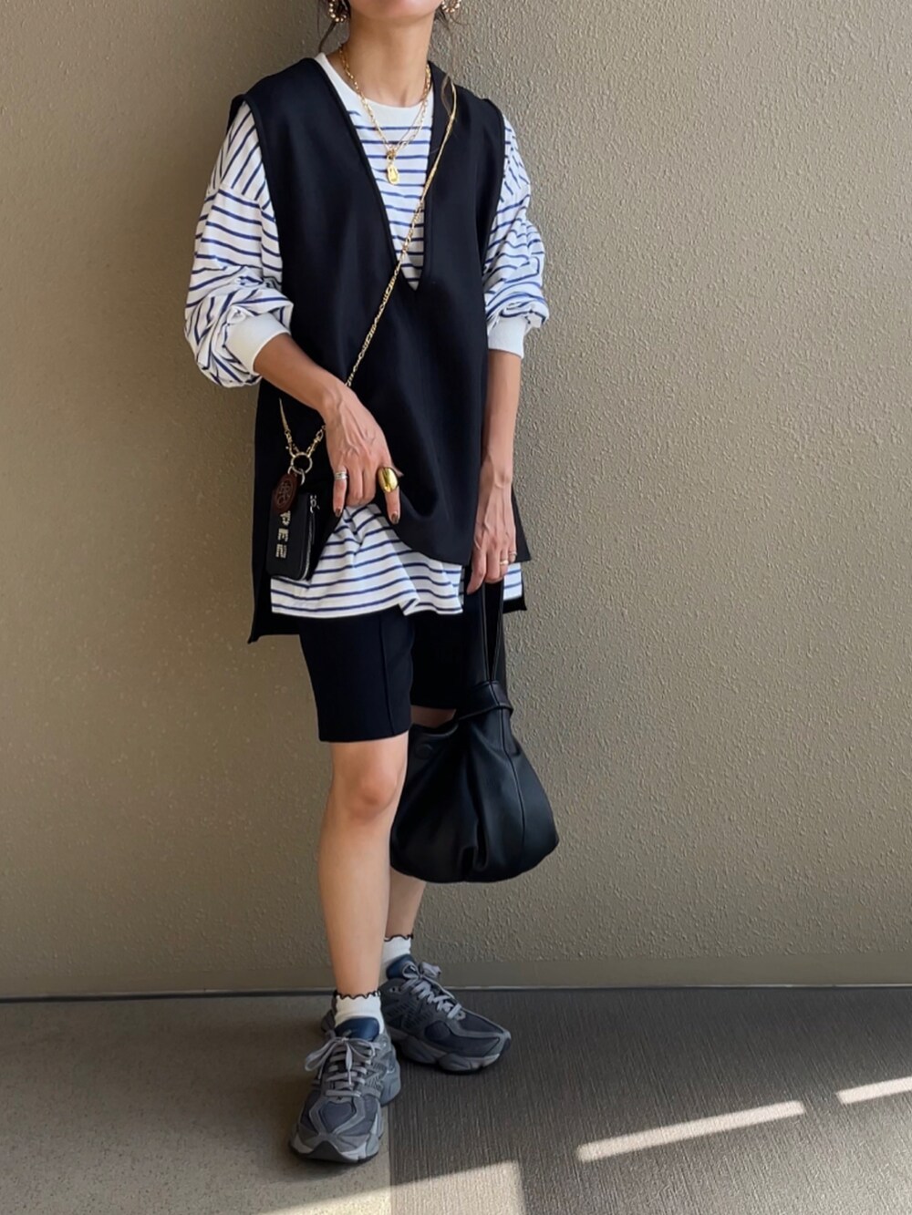 ブルー系のデニムパンツ、グリーン系のベスト、ブラック系のハンドバッグを着用したレディースの秋コーディネートの4枚目の写真