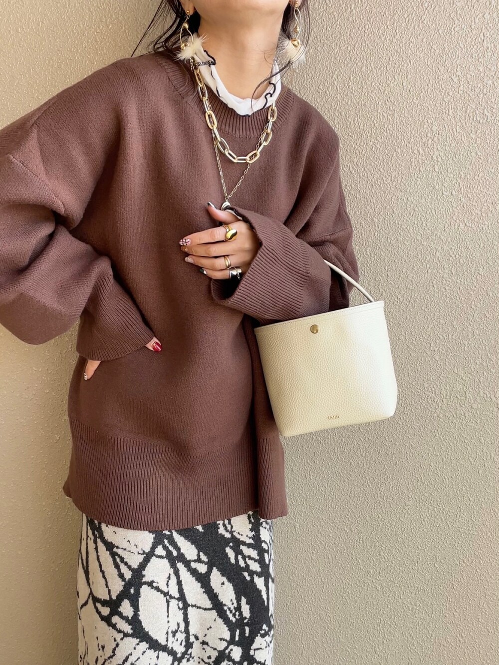 ブラウン系のニット/セーター、ベージュ系のスカート、ベージュ系のその他アウターを着用したレディースの冬コーディネートの3枚目の写真