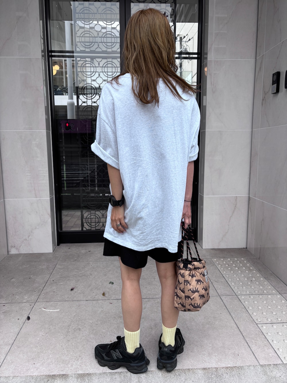 グレー系のTシャツ/カットソー、ベージュ系のショルダーバッグ、ブラック系のスニーカーを着用したレディースの夏コーディネートの2枚目の写真