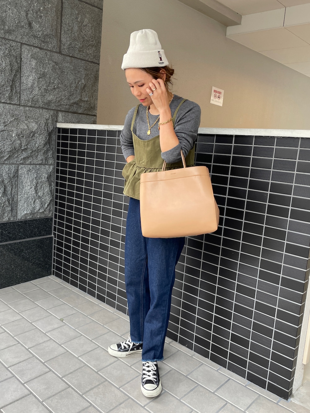 ブルー系のデニムパンツ、グレー系のニット/セーター、グリーン系のキャミソールを着用したレディースの秋コーディネートの3枚目の写真