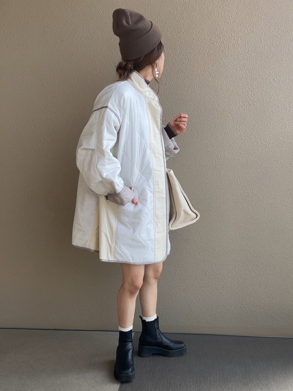 ホワイト系のその他アウター、ベージュ系のバッグ、ブラック系のブーツを着用したレディースの秋コーディネートの4枚目の写真