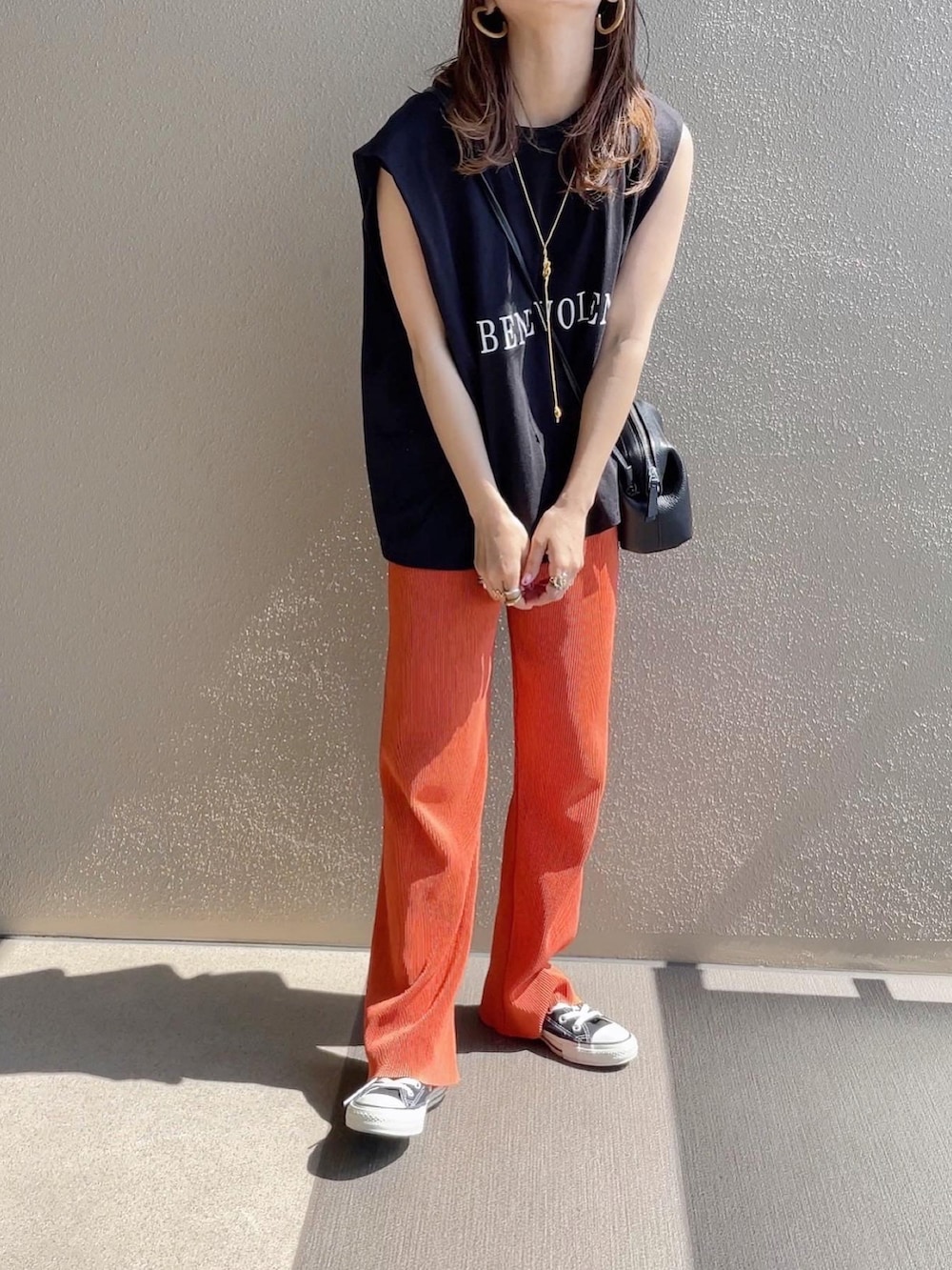 ブラック系のTシャツ/カットソー、オレンジ系のその他パンツ、ホワイト系のワンピースを着用したレディースの春コーディネートの4枚目の写真