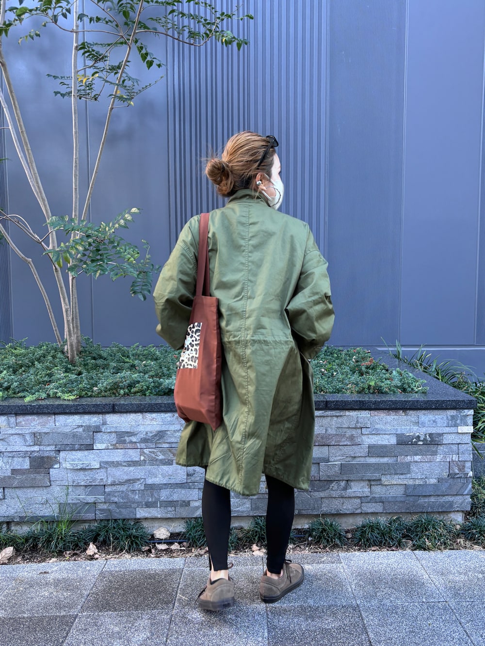 グレー系のTシャツ/カットソー、ブラウン系のトートバッグ、グリーン系のモッズコートを着用したレディースの秋コーディネートの2枚目の写真