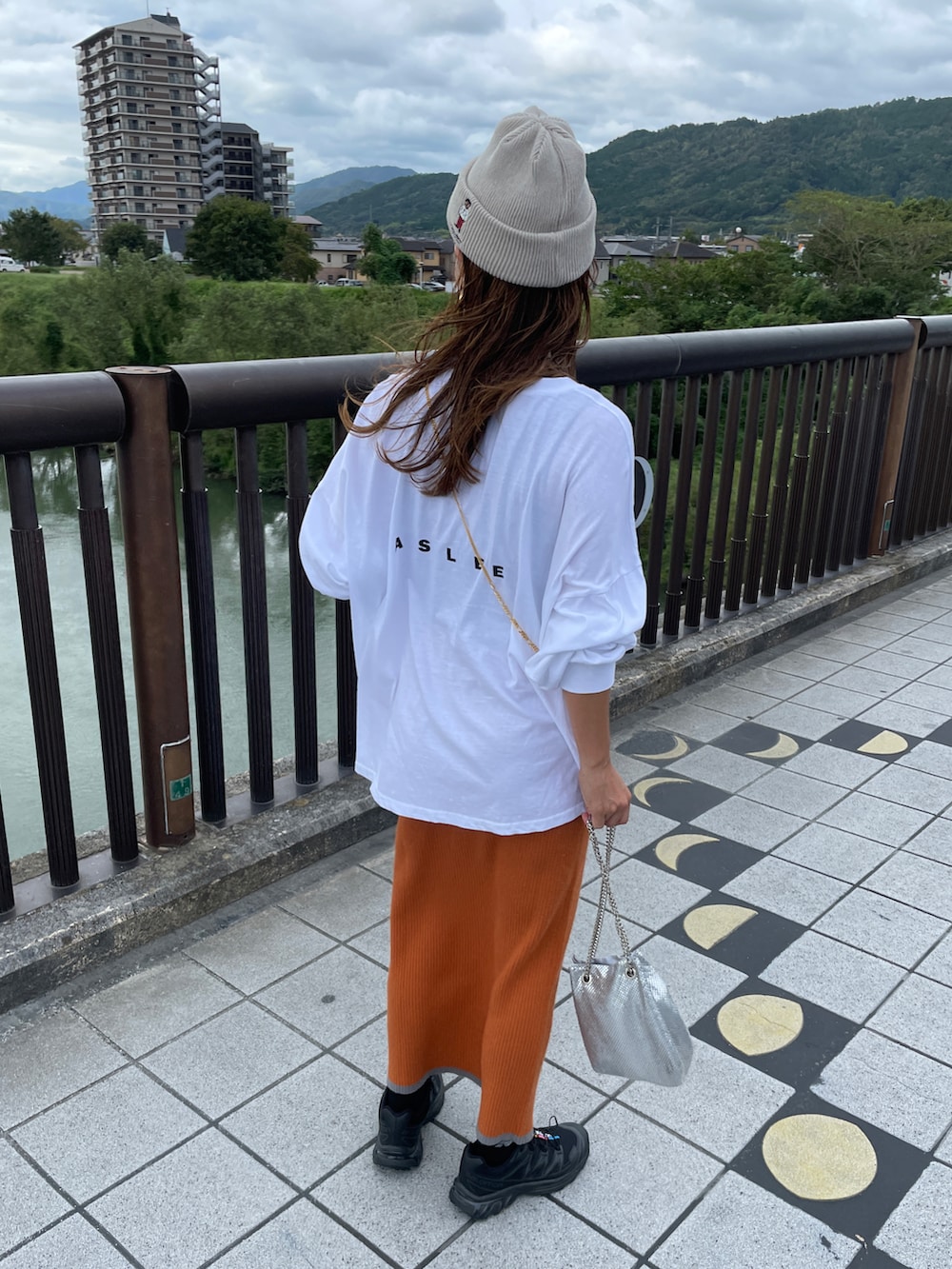 オレンジ系のスカート、ホワイト系のTシャツ/カットソー、シルバー系のショルダーバッグを着用したレディースの秋コーディネートの4枚目の写真