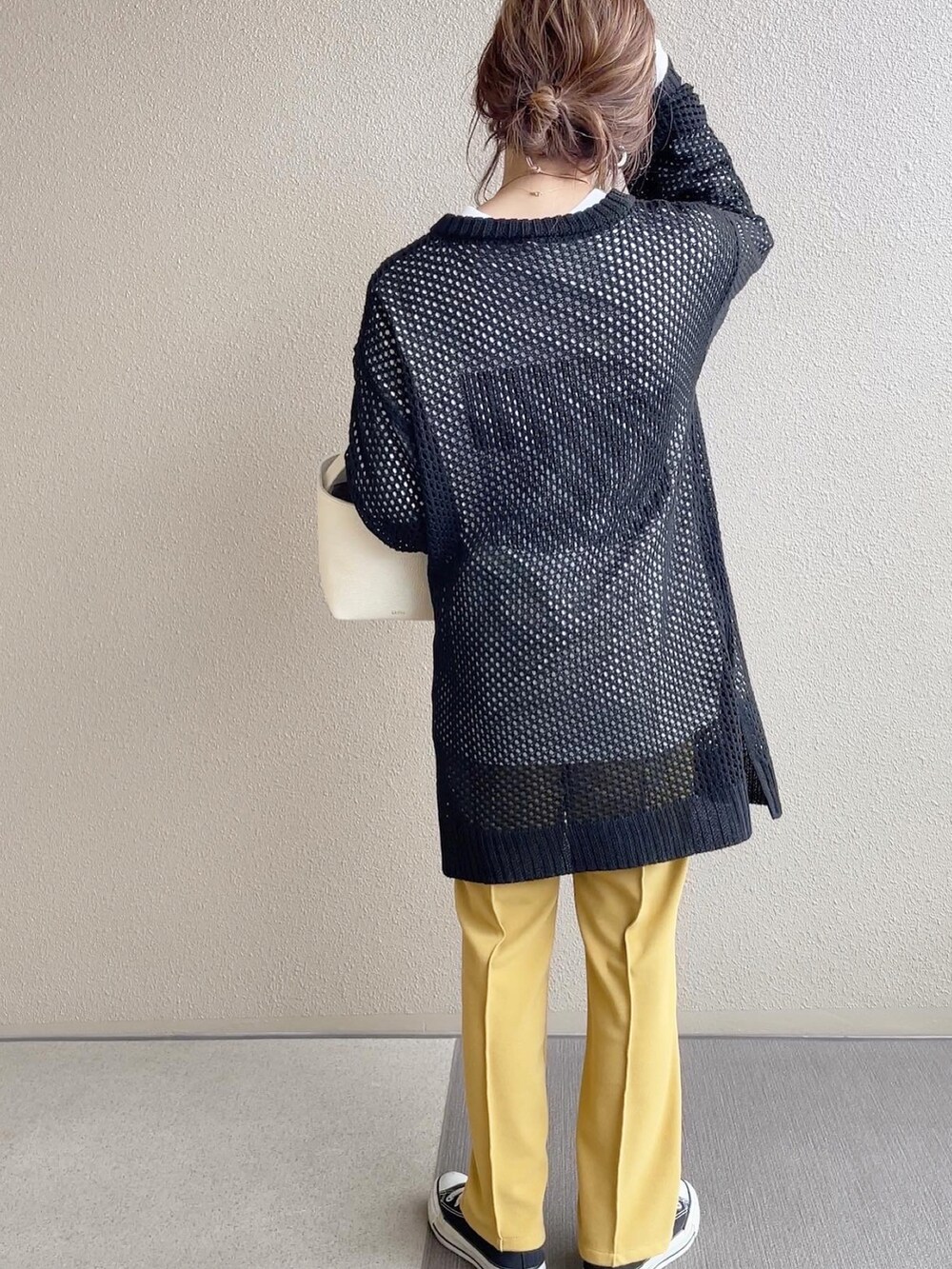 ブラック系のニット/セーター、イエロー系のその他パンツ、ホワイト系のTシャツ/カットソーを着用したレディースの冬コーディネートの3枚目の写真