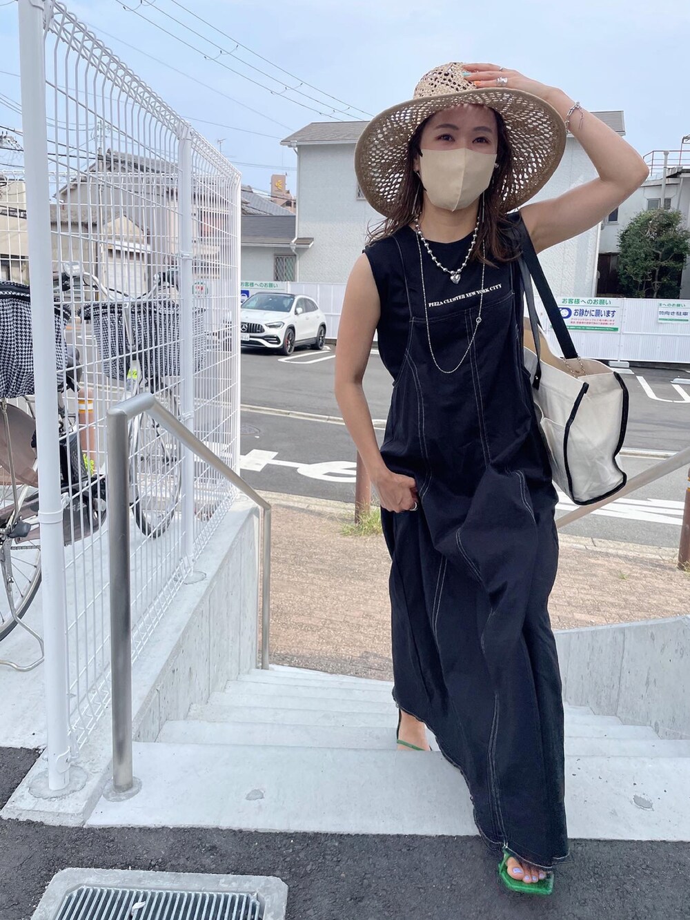 ブラック系のワンピース、ホワイト系のトートバッグ、グリーン系のサンダルを着用したレディースの夏コーディネートの2枚目の写真