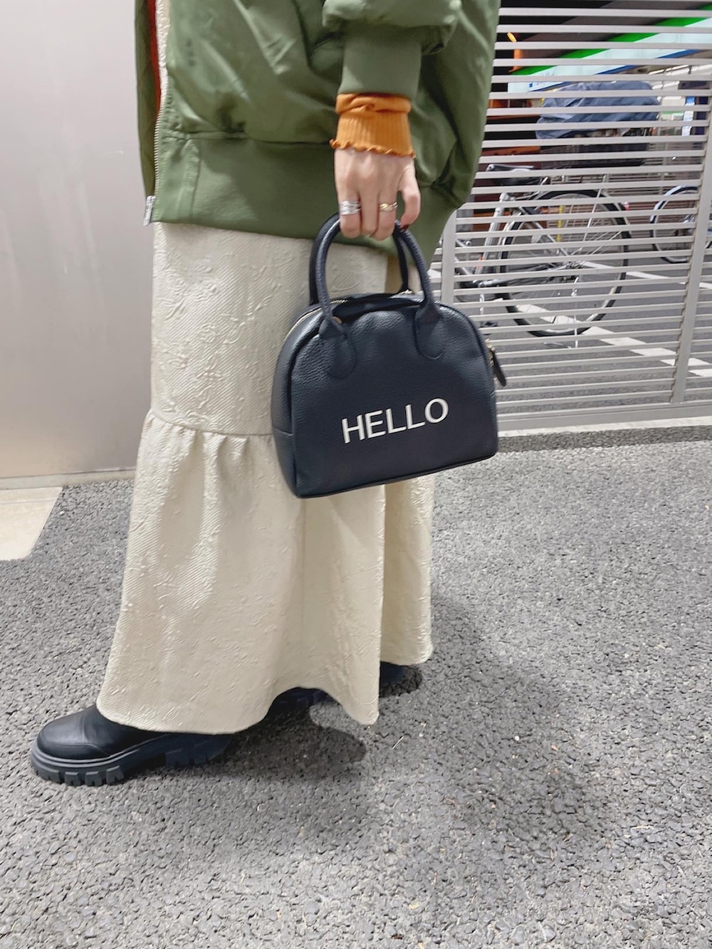 ブラック系のハンドバッグ、グリーン系のMA-1、オレンジ系のTシャツ/カットソーを着用したレディースの秋コーディネートの5枚目の写真