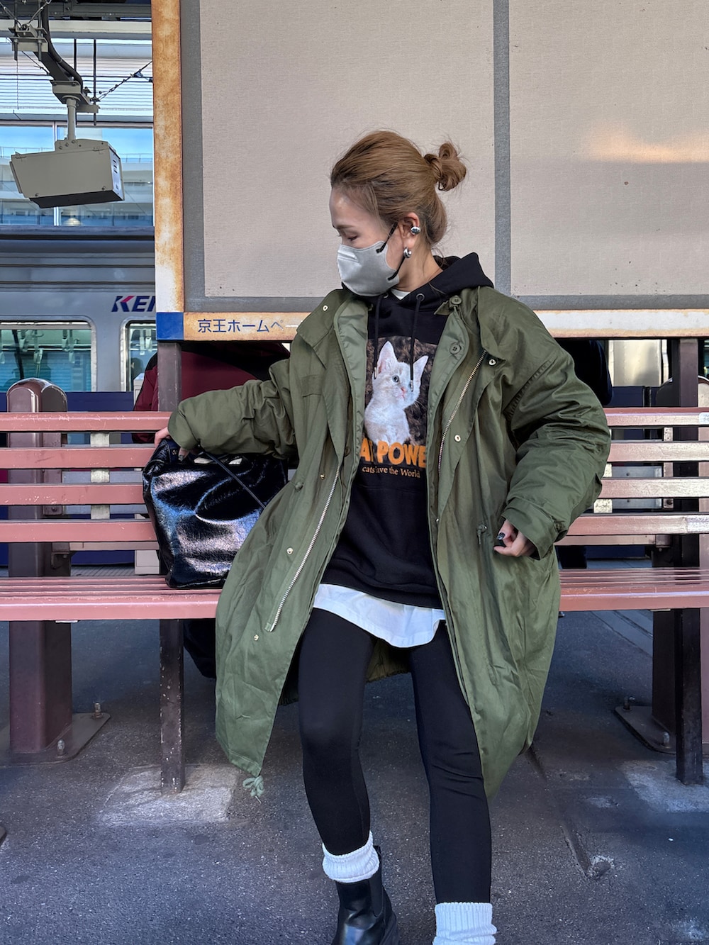 グリーン系のモッズコート、ブラック系のパーカーを着用したレディースの冬コーディネートの2枚目の写真