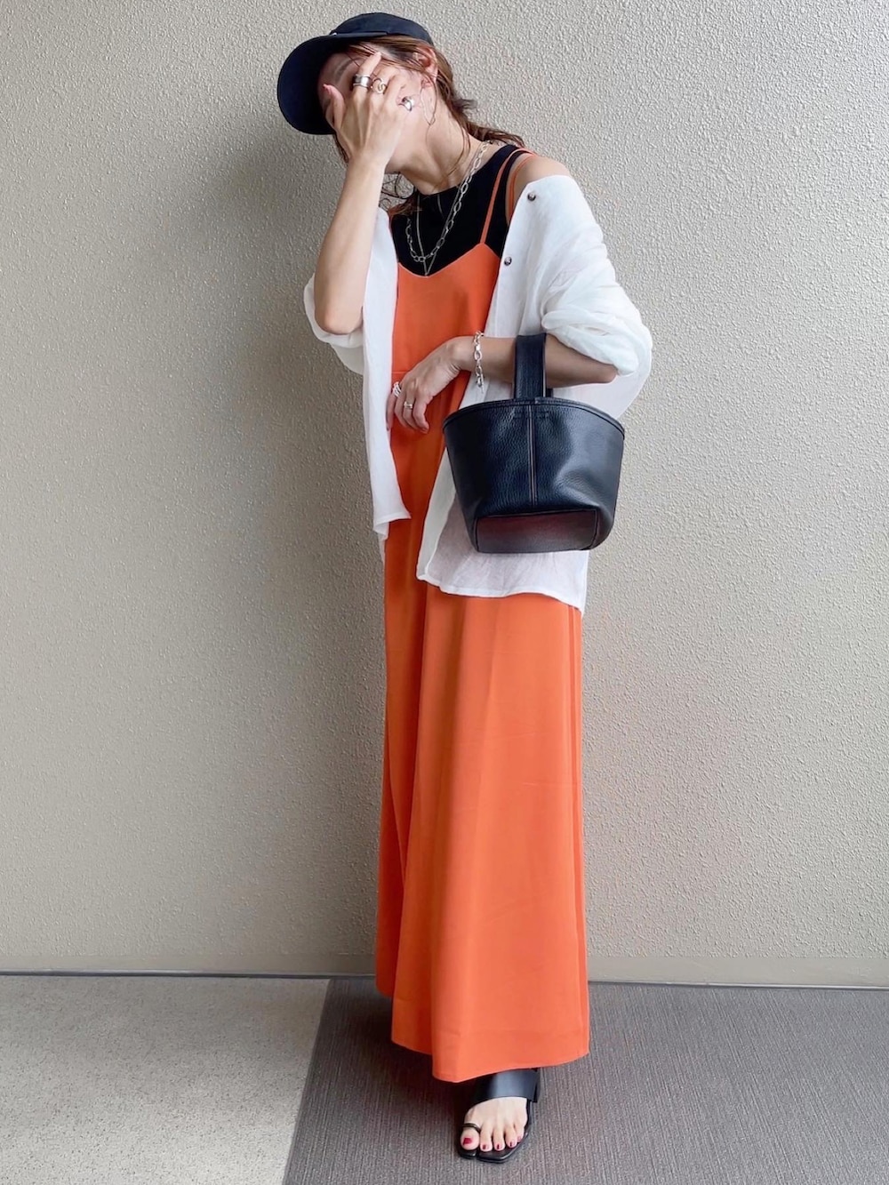 オレンジ系のワンピース、ブラック系のタンクトップ、ホワイト系のシャツ/ブラウスを着用したレディースの春コーディネートの4枚目の写真