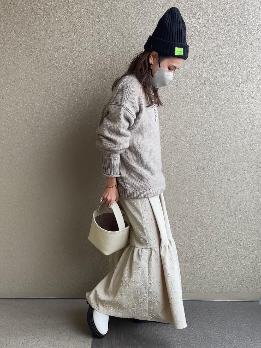 ベージュ系のニット/セーター、ブラウン系のデニムパンツ、ベージュ系のワンピースを着用したレディースの秋コーディネートの4枚目の写真