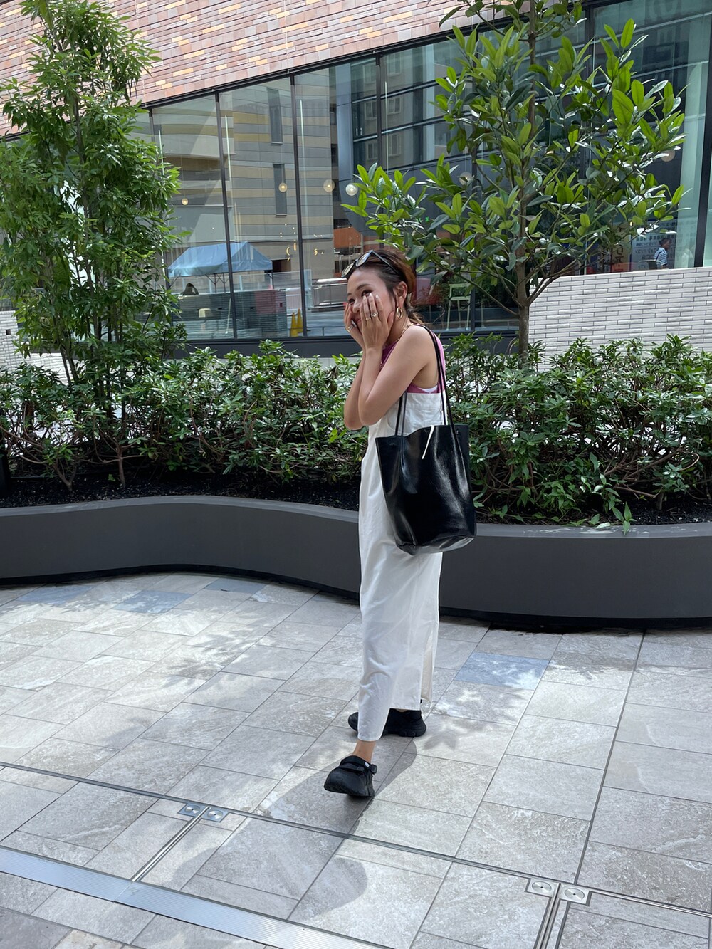 ピンク系のTシャツ/カットソー、ホワイト系のジャンパースカート、ブラック系のショルダーバッグを着用したレディースの夏コーディネートの3枚目の写真