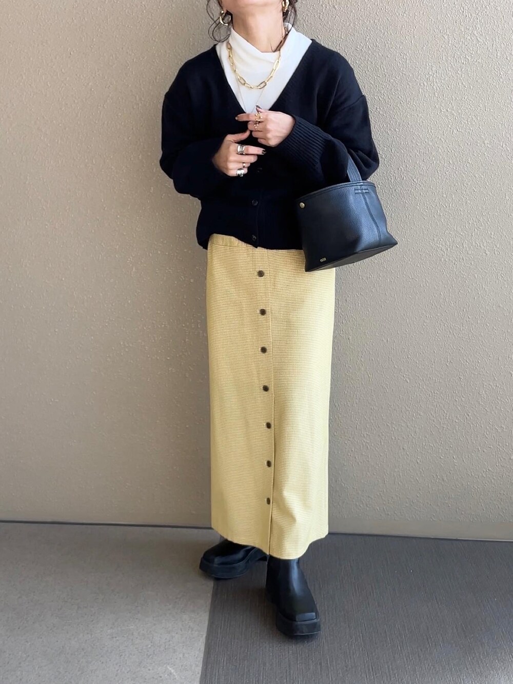 ブラック系のカーディガン/ボレロ、イエロー系のスカート、ホワイト系のノーカラージャケットを着用したレディースの冬コーディネートの4枚目の写真