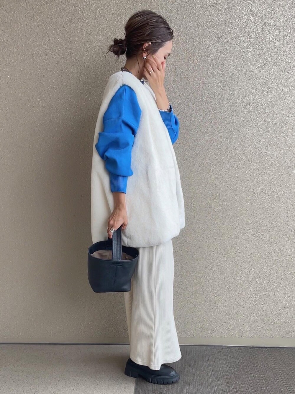 ブルー系のニット/セーター、ベージュ系のスカート、ホワイト系のベストを着用したレディースの秋コーディネートの4枚目の写真