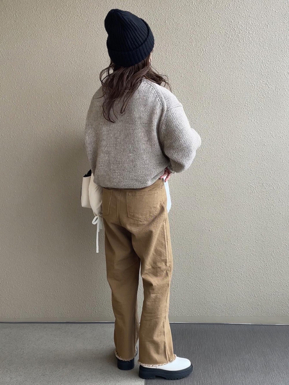 ベージュ系のニット/セーター、ブラウン系のデニムパンツ、ベージュ系のワンピースを着用したレディースの秋コーディネートの2枚目の写真