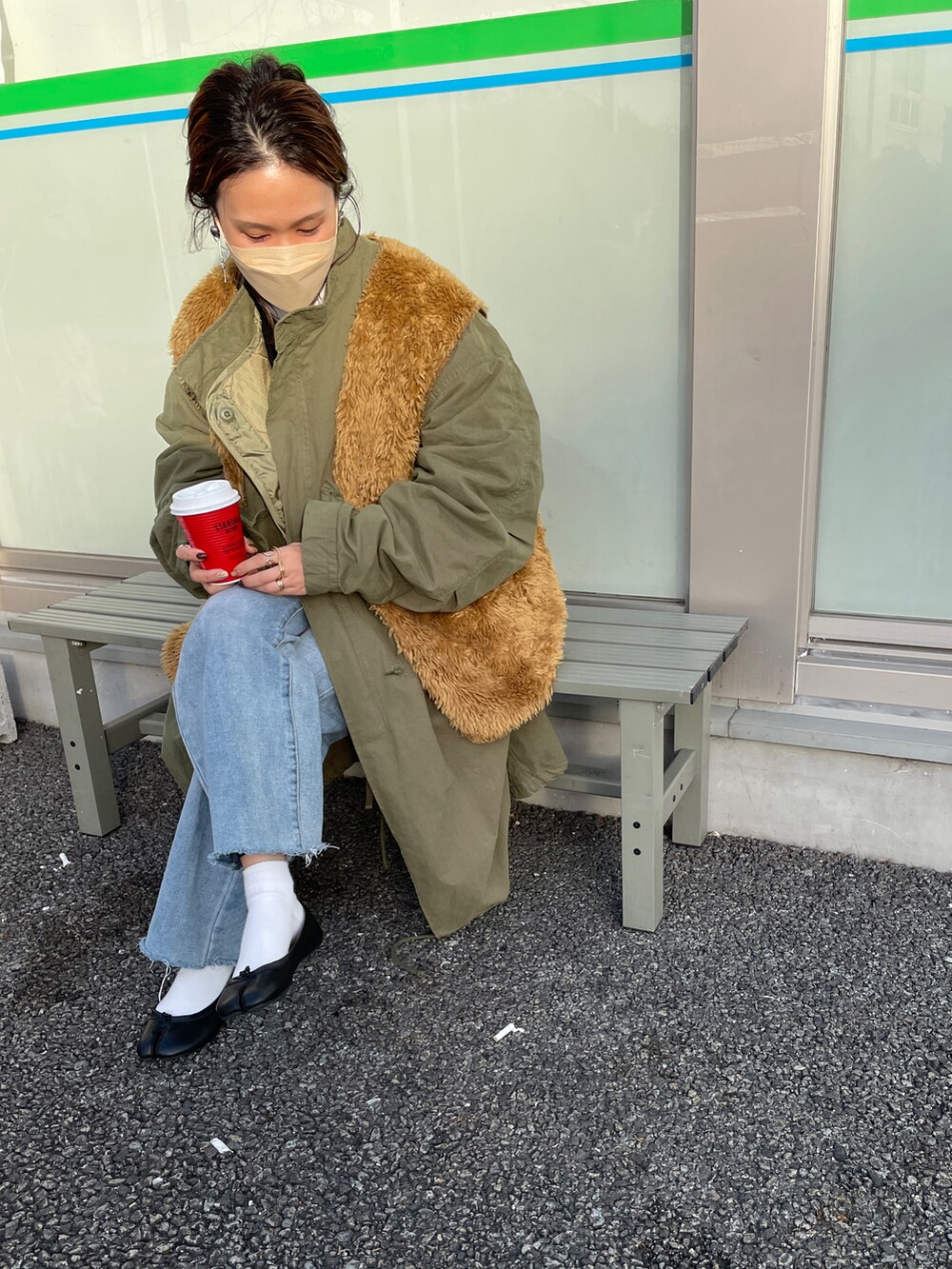 グリーン系のモッズコート、ブラウン系のベスト、ブラック系のニット/セーターを着用したレディースの冬コーディネートの2枚目の写真