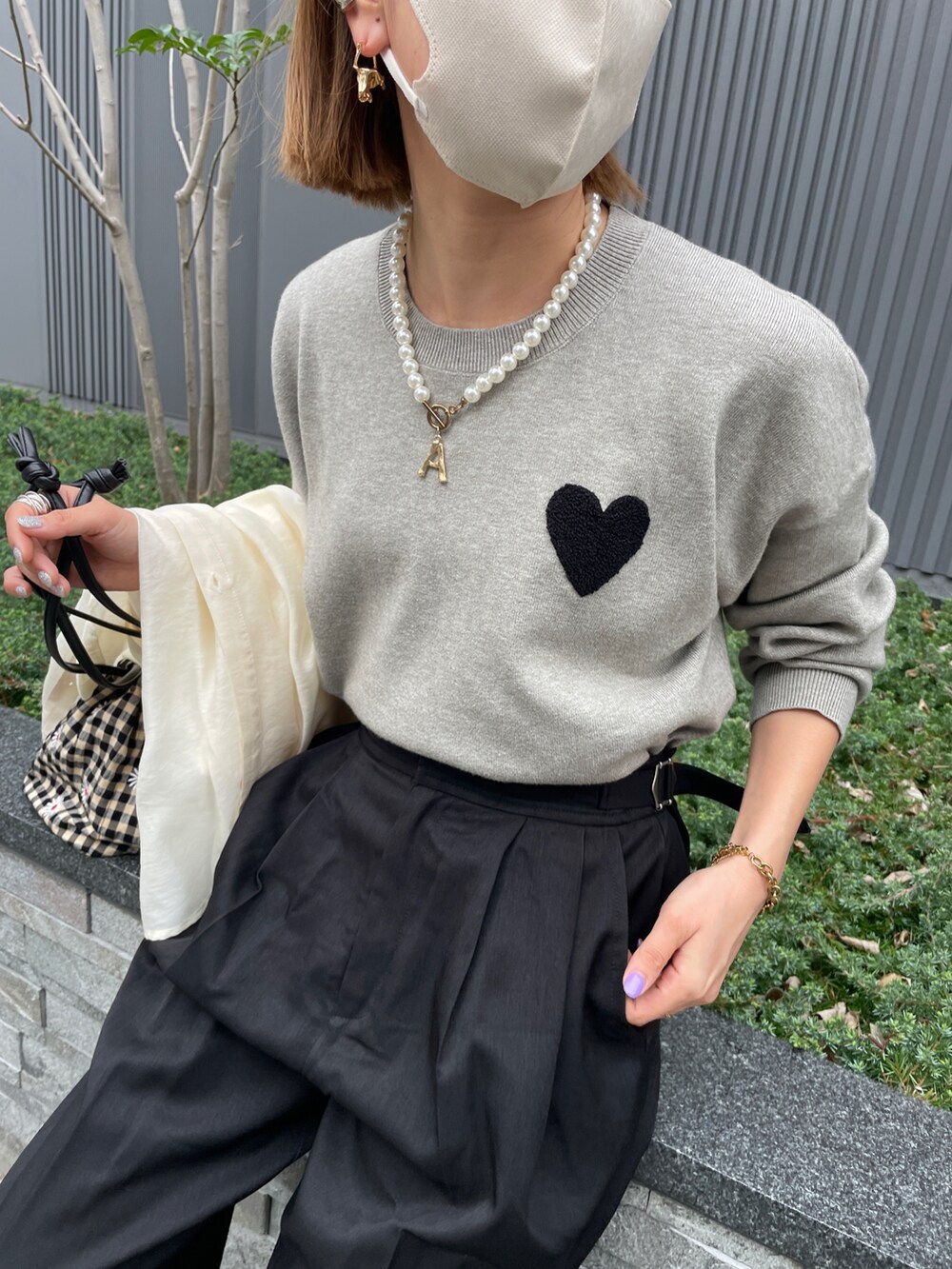 グレー系のニット/セーター、ブラック系のスラックス、その他のハンドバッグを着用したレディースの春コーディネートの2枚目の写真