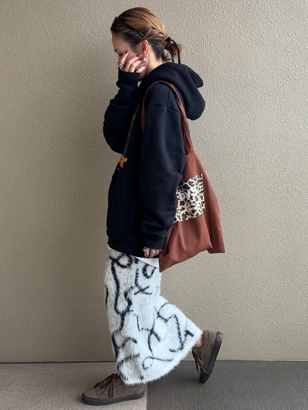ホワイト系のスカート、ブラウン系のトートバッグ、ブラック系のパーカーを着用したレディースの秋コーディネートの2枚目の写真