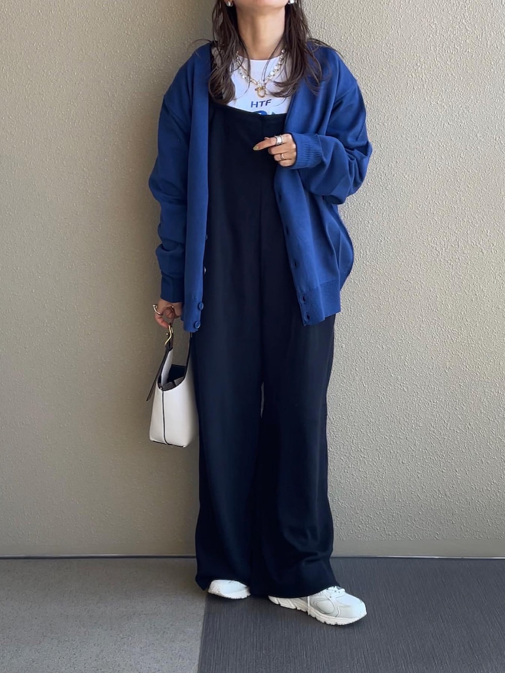 ブルー系のカーディガン/ボレロ、ブラック系のサロペット/オーバーオール、ホワイト系のスニーカーを着用したレディースの秋コーディネートの3枚目の写真