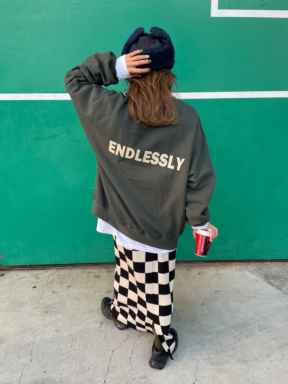 グリーン系のスウェット、ホワイト系のスカート、ブルー系のハットを着用したレディースの秋コーディネートの2枚目の写真