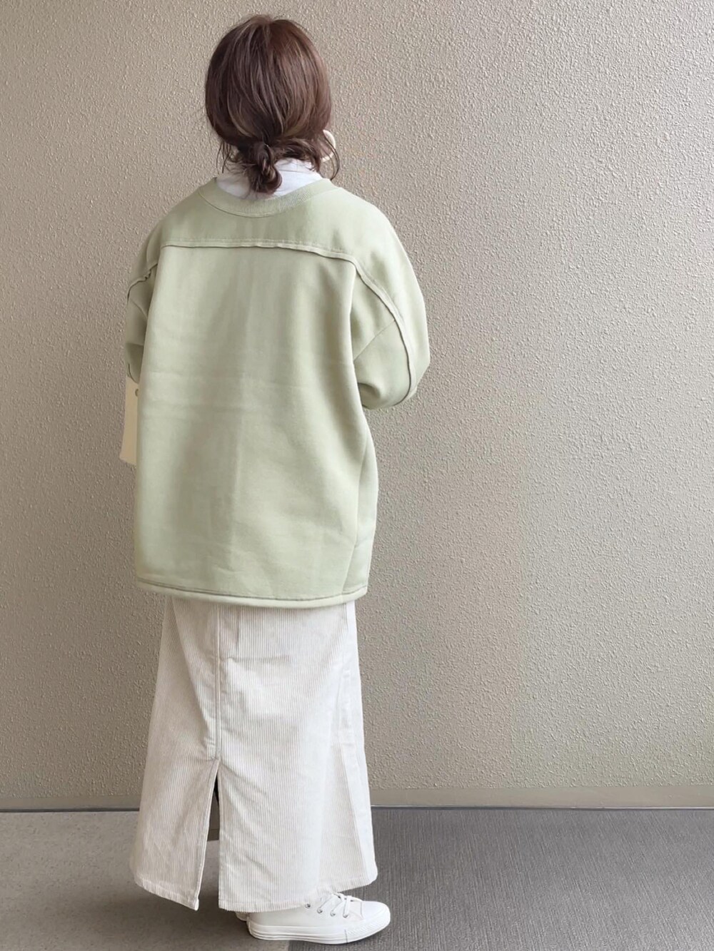 グリーン系のカーディガン/ボレロ、ホワイト系のスカート、ホワイト系のスニーカーを着用したレディースの冬コーディネートの3枚目の写真