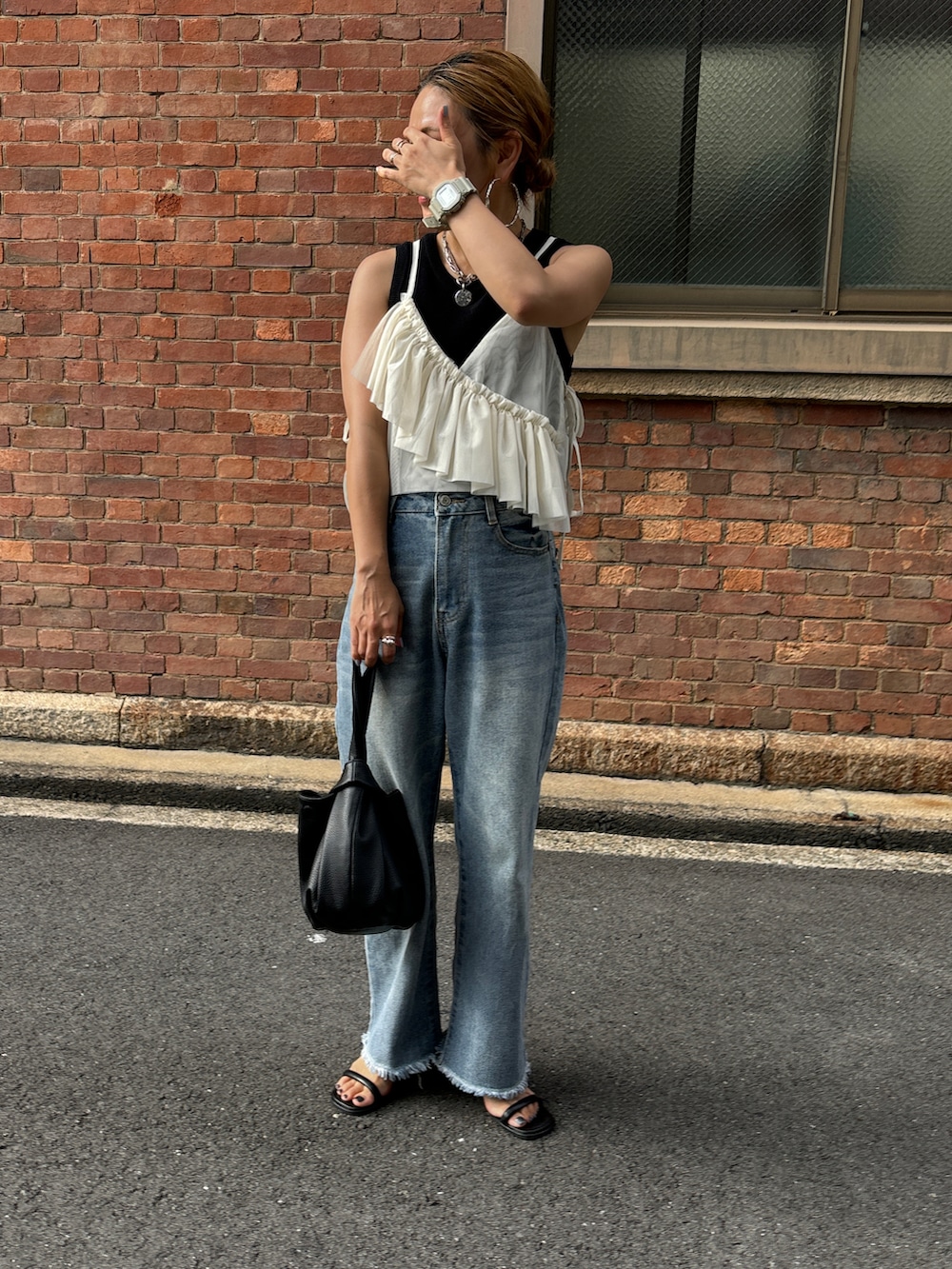 ホワイト系のキャミソール、ブルー系のデニムパンツ、ブラック系のハンドバッグを着用したレディースの夏コーディネートの3枚目の写真
