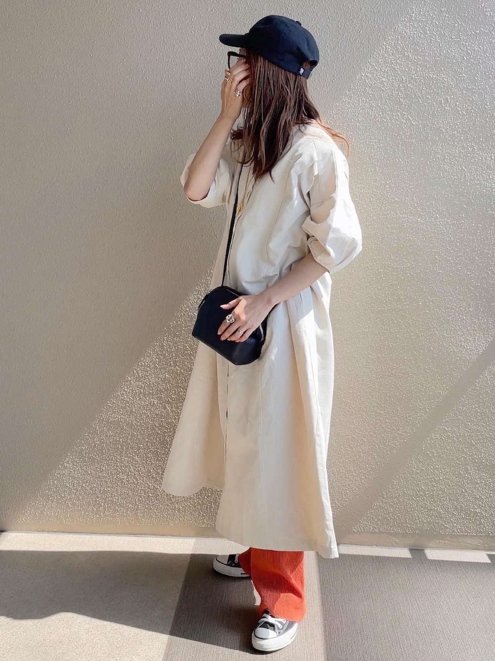 ブラック系のTシャツ/カットソー、オレンジ系のその他パンツ、ホワイト系のワンピースを着用したレディースの春コーディネートの3枚目の写真