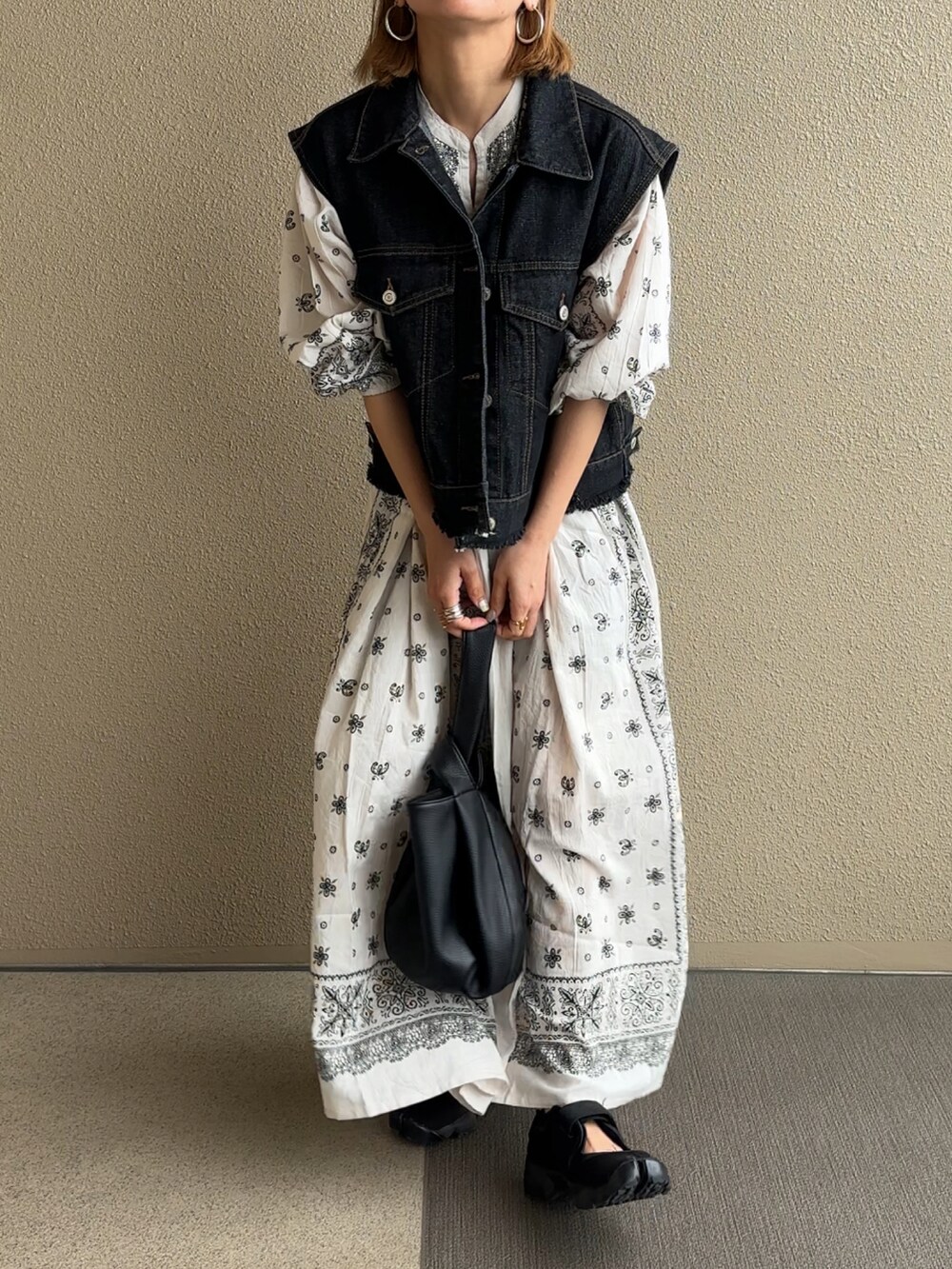 ブラック系のベストを着用したレディースの春コーディネートの2枚目の写真