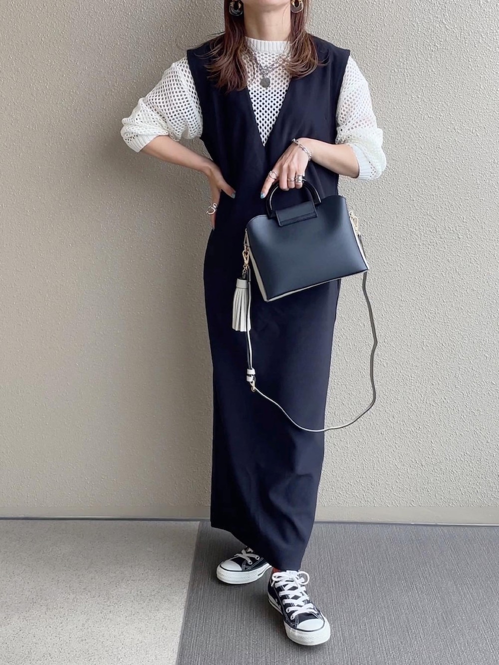 ブラック系のジャンパースカート、ホワイト系のトップス、ホワイト系のニット/セーターを着用したレディースの春コーディネートの3枚目の写真