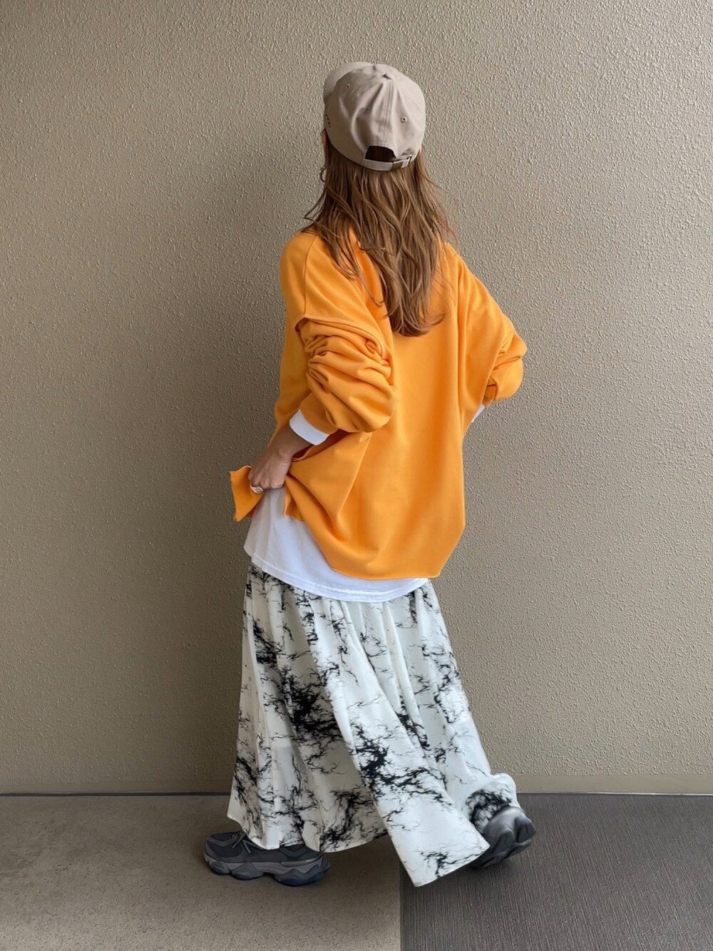 オレンジ系のスウェット、ホワイト系のスカートを着用したレディースの冬コーディネートの2枚目の写真