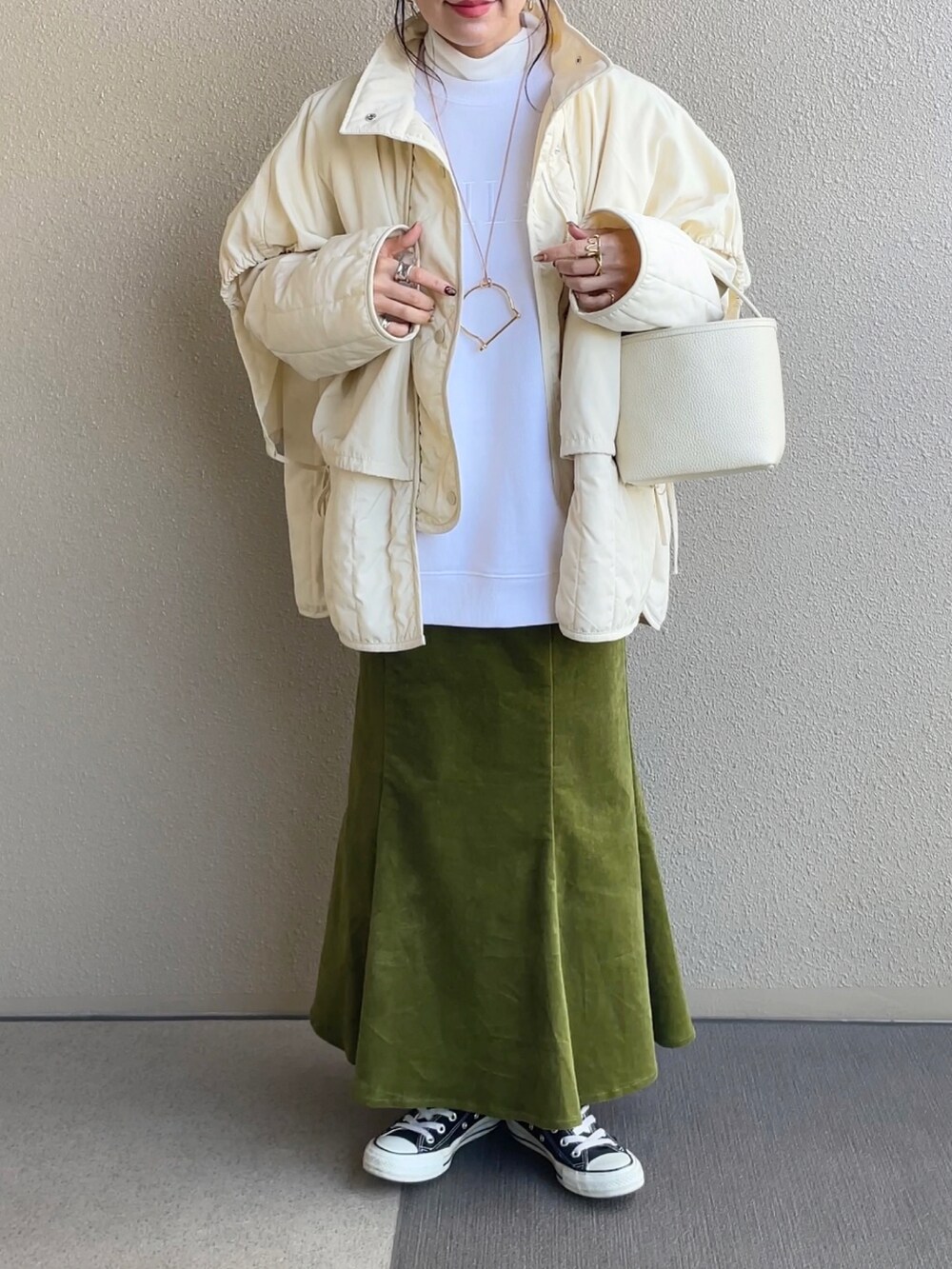 グリーン系のスカート、ホワイト系のスウェット、ブラック系のその他アウターを着用したレディースの冬コーディネートの3枚目の写真