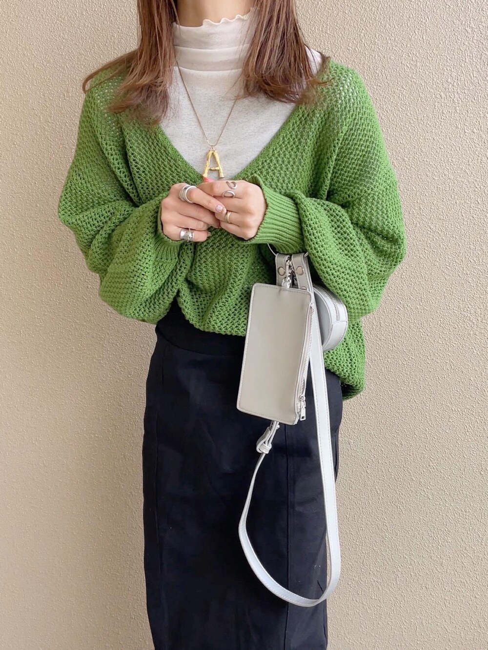 グリーン系のニット/セーター、ブラック系のスカート、ホワイト系のTシャツ/カットソーを着用したレディースの冬コーディネートの2枚目の写真