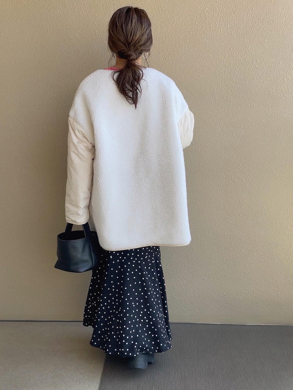 ホワイト系のノーカラージャケット、ピンク系のスウェット、ブラック系のスカートを着用したレディースの秋コーディネートの3枚目の写真