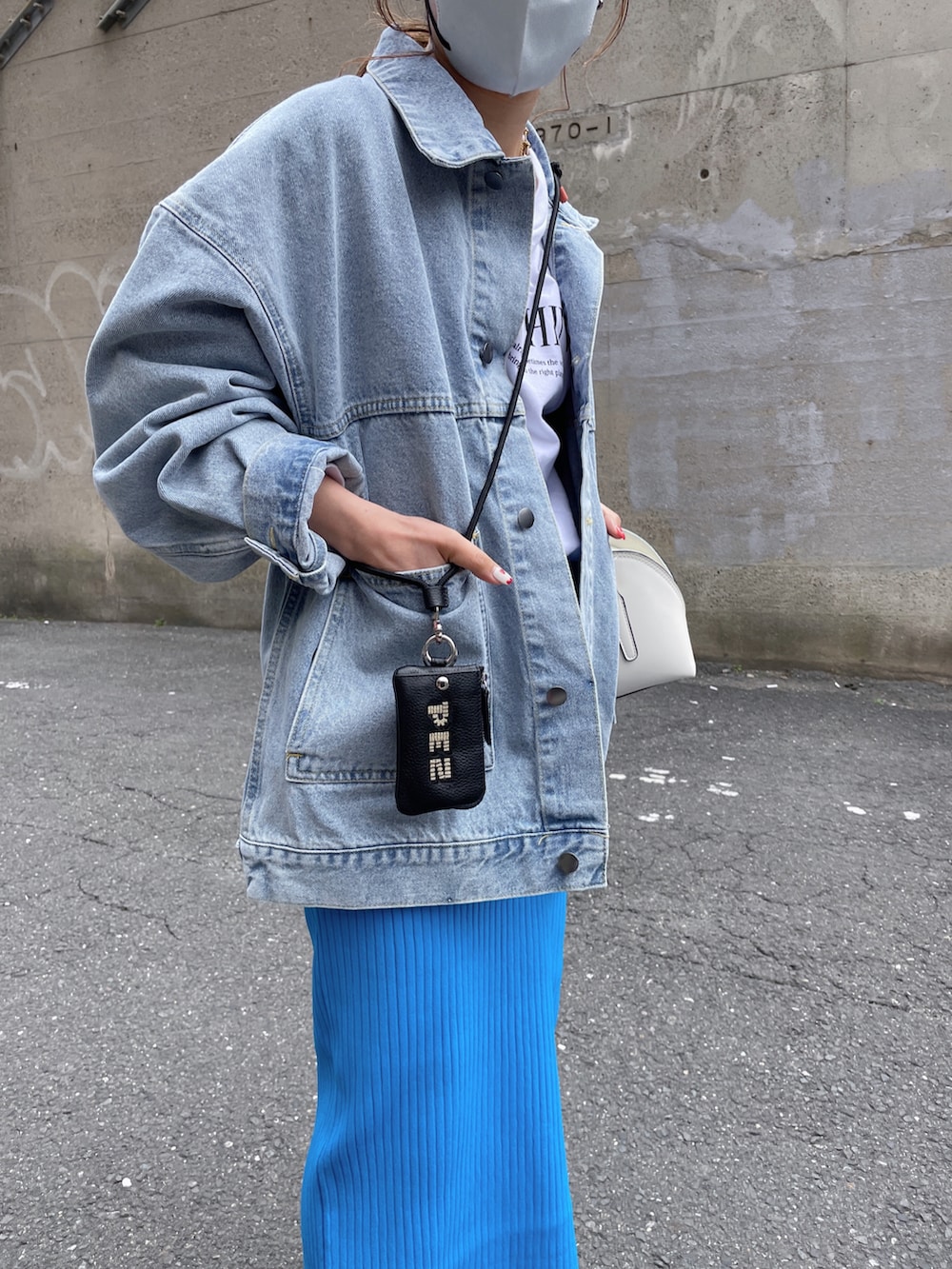 ブルー系のデニムジャケット、ホワイト系のスウェット、ブラック系のカードケースを着用したレディースの春コーディネートの2枚目の写真