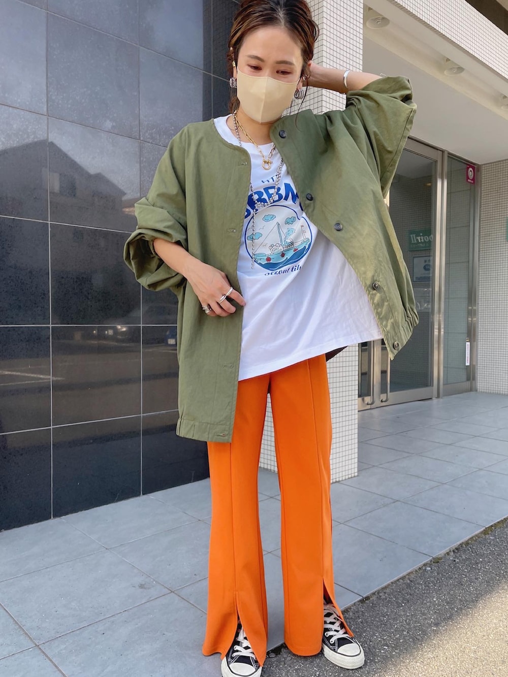 オレンジ系のスラックス、グリーン系のノーカラージャケットを着用したレディースの秋コーディネートの3枚目の写真