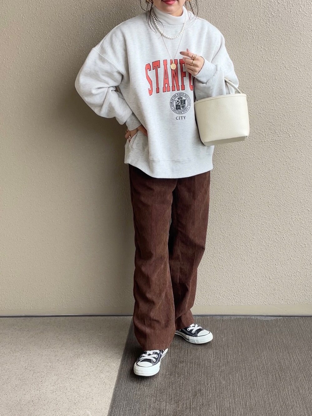 ホワイト系のノーカラージャケット、グレー系のスウェット、ブラウン系のパンツを着用したレディースの冬コーディネートの2枚目の写真