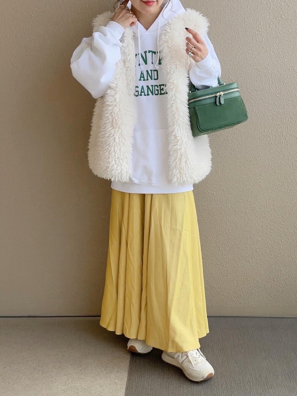 ホワイト系のパーカー、ホワイト系のベスト、ベージュ系のスニーカーを着用したレディースの冬コーディネートの4枚目の写真