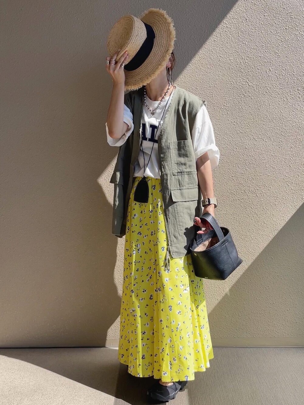 ホワイト系のTシャツ/カットソー、ブラック系のサンダル、グリーン系のベストを着用したレディースの夏コーディネートの4枚目の写真