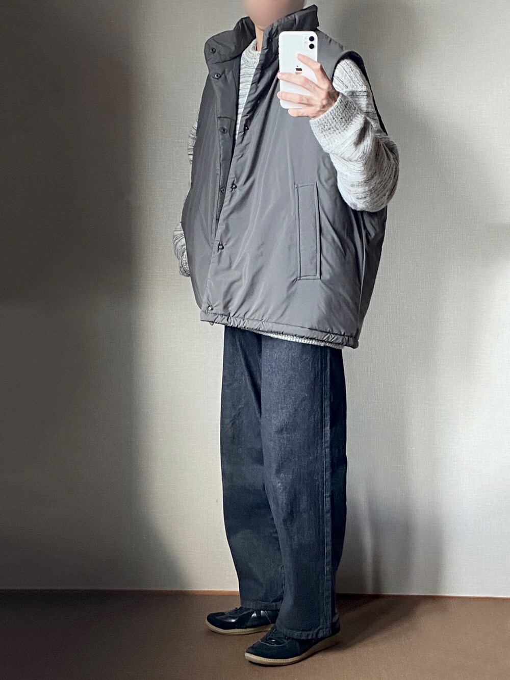 グレー系のベスト、グレー系のニット/セーター、グレー系のデニムパンツを着用したメンズの秋コーディネートの2枚目の写真