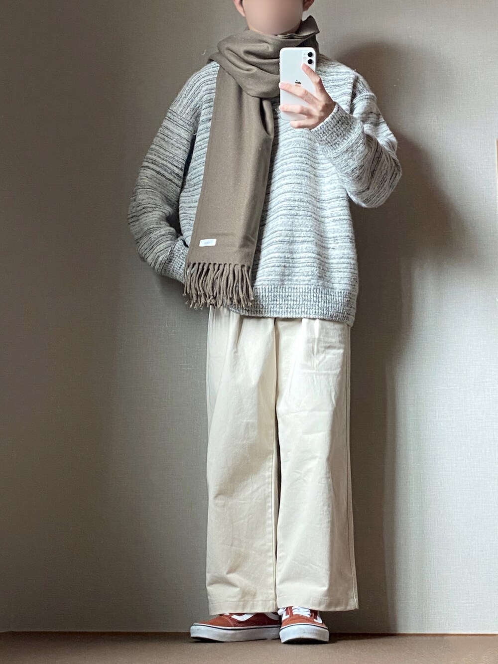 グレー系のニット/セーター、ホワイト系のチノパンツ、ブラウン系のスニーカーを着用したメンズの冬コーディネートの2枚目の写真